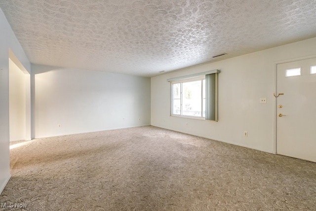 carpeted empty room featuring a textured ceiling