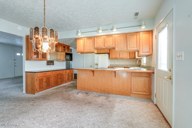 kitchen with decorative light fixtures, sink, light carpet, and kitchen peninsula