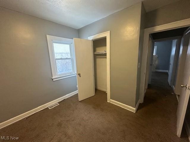 unfurnished bedroom with a closet and dark carpet