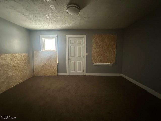 carpeted empty room featuring a textured ceiling