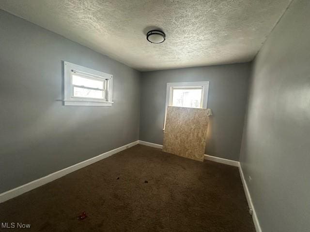 empty room with a textured ceiling and dark colored carpet