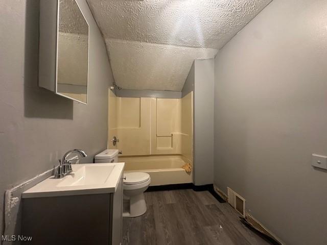 full bathroom featuring toilet, vanity, hardwood / wood-style flooring, shower / bathtub combination, and a textured ceiling