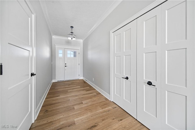 entrance foyer featuring a textured ceiling, ornamental molding, and light wood-type flooring