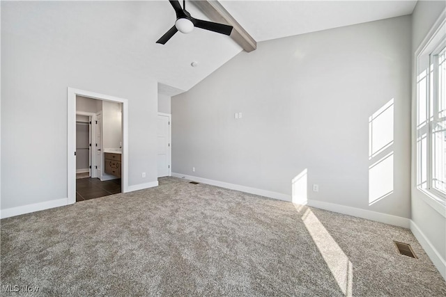 unfurnished bedroom with ceiling fan, vaulted ceiling with beams, connected bathroom, and dark colored carpet