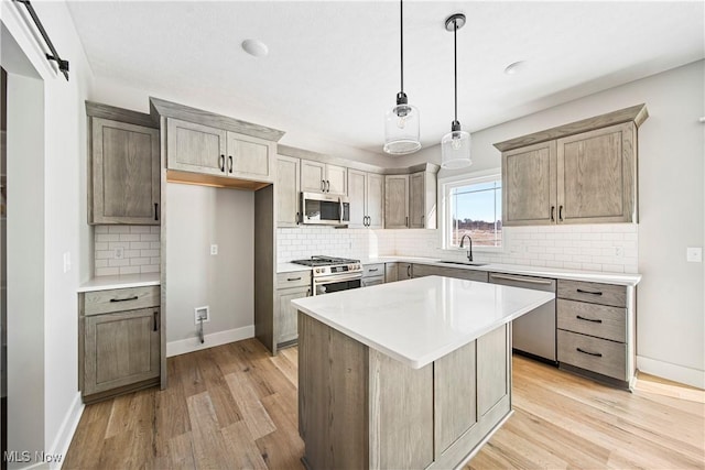 kitchen with decorative light fixtures, a kitchen island, sink, light hardwood / wood-style flooring, and stainless steel appliances