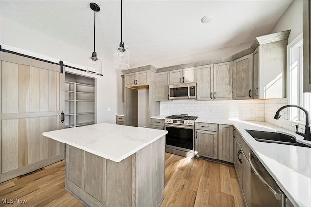 kitchen featuring appliances with stainless steel finishes, backsplash, hanging light fixtures, light hardwood / wood-style flooring, and sink