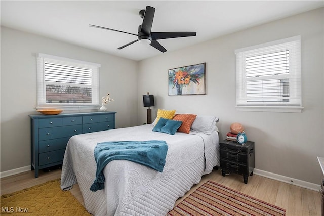 bedroom featuring ceiling fan, light hardwood / wood-style floors, and multiple windows