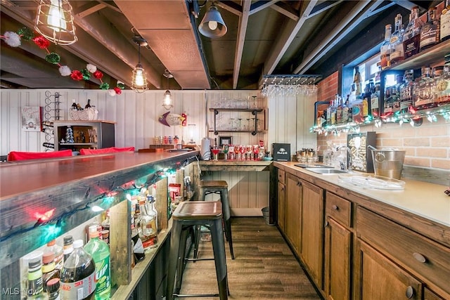 bar featuring sink, pendant lighting, and dark wood-type flooring