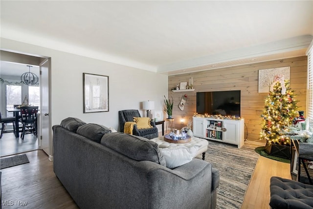 living room featuring a notable chandelier, wood walls, and hardwood / wood-style floors