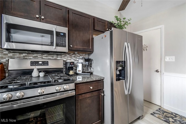 kitchen featuring ceiling fan, tasteful backsplash, stainless steel appliances, dark stone counters, and dark brown cabinetry