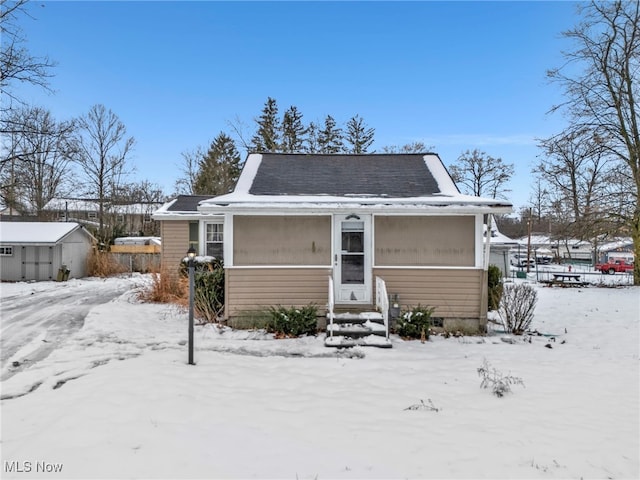 snow covered back of property featuring a storage unit