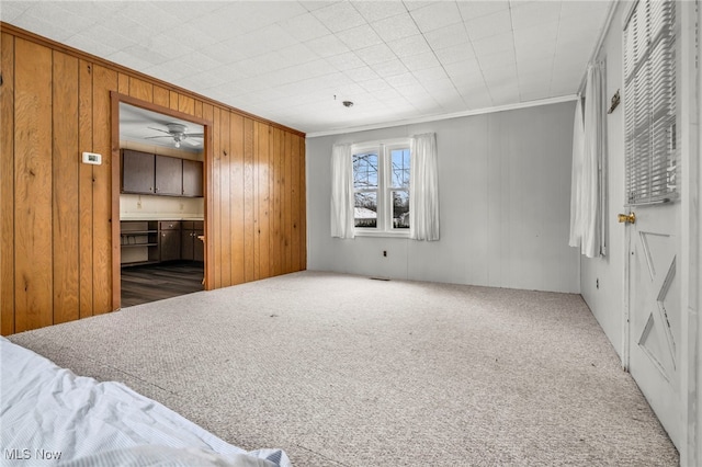 carpeted bedroom featuring wood walls and crown molding