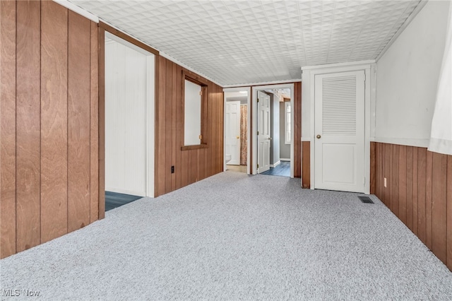 spare room featuring wood walls and dark carpet