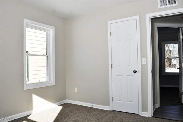 empty room with a healthy amount of sunlight and dark carpet