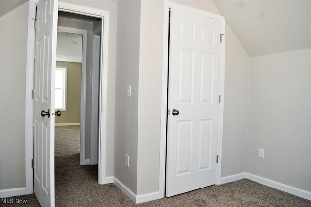 hallway with carpet flooring and lofted ceiling