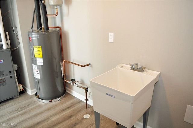 utility room with electric water heater and sink