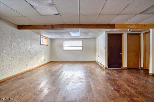 basement with dark wood-type flooring and baseboard heating