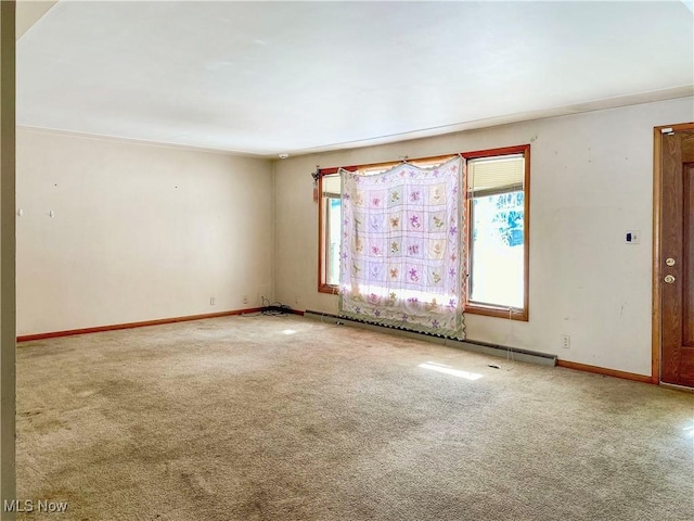 carpeted spare room featuring a wealth of natural light and baseboard heating