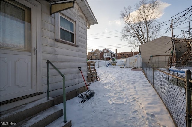 snowy yard featuring a storage unit