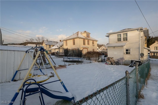 yard covered in snow featuring a playground and a trampoline