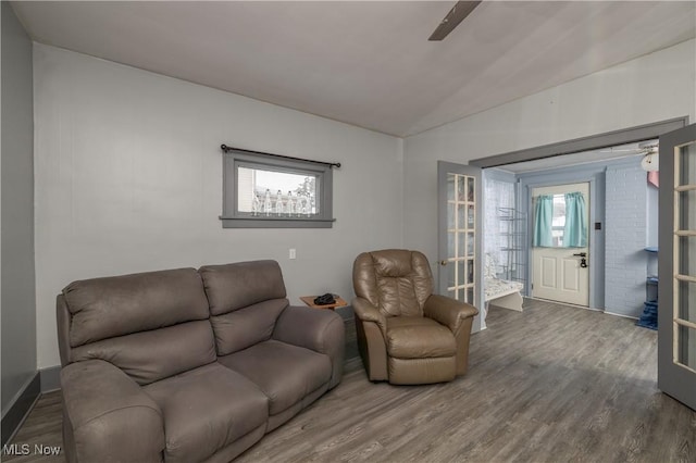 living room with hardwood / wood-style flooring, french doors, and vaulted ceiling