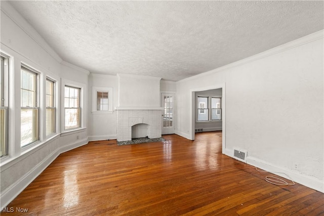 unfurnished living room featuring crown molding, hardwood / wood-style floors, a textured ceiling, and a brick fireplace