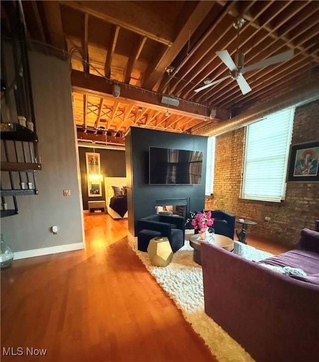 living room with a fireplace, wood-type flooring, brick wall, and ceiling fan