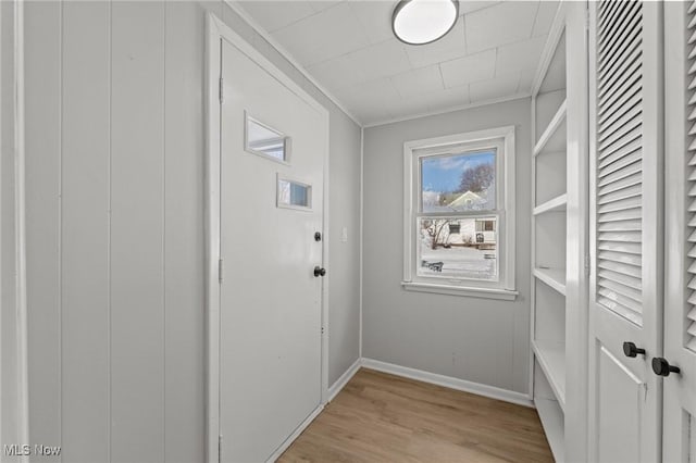 entryway with ornamental molding and light wood-type flooring