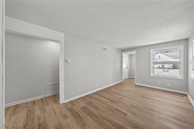 spare room with light hardwood / wood-style floors and a textured ceiling