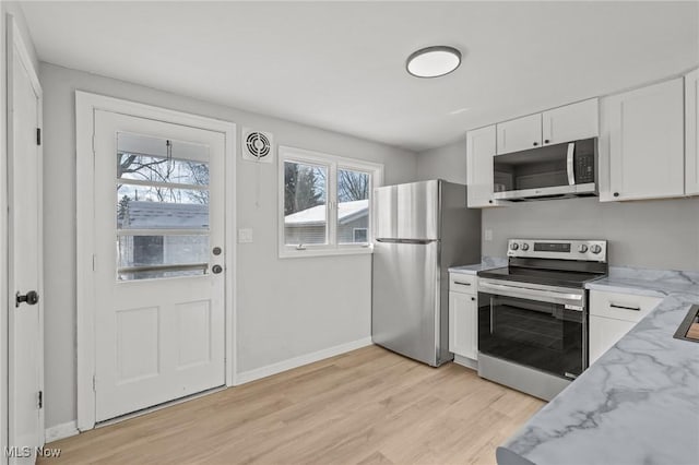 kitchen with light wood-type flooring, stainless steel appliances, white cabinetry, and light stone countertops