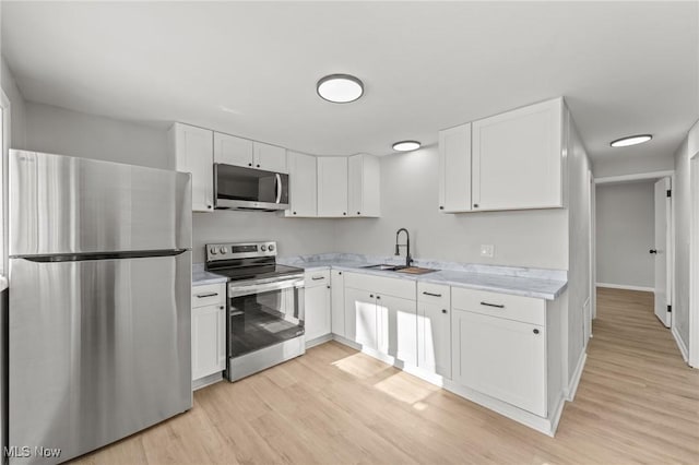 kitchen with sink, white cabinetry, light hardwood / wood-style flooring, and stainless steel appliances