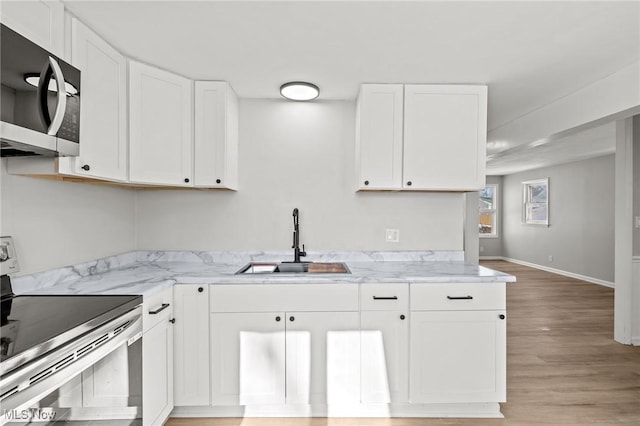 kitchen featuring appliances with stainless steel finishes, white cabinetry, sink, light hardwood / wood-style flooring, and light stone counters