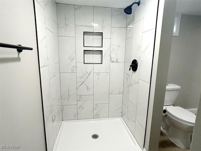 bathroom with toilet and tiled shower