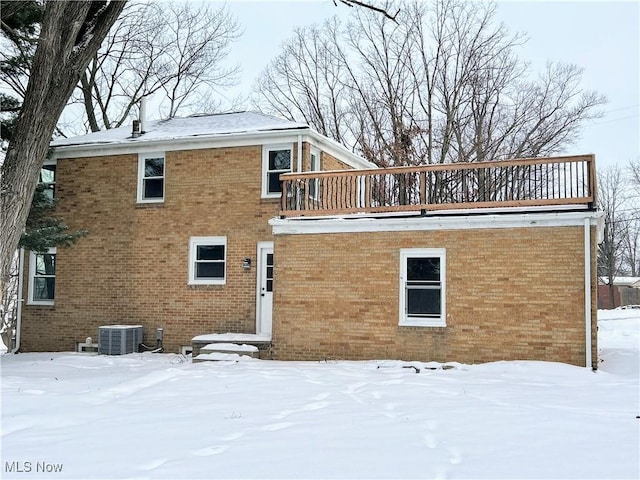 snow covered house featuring central AC unit