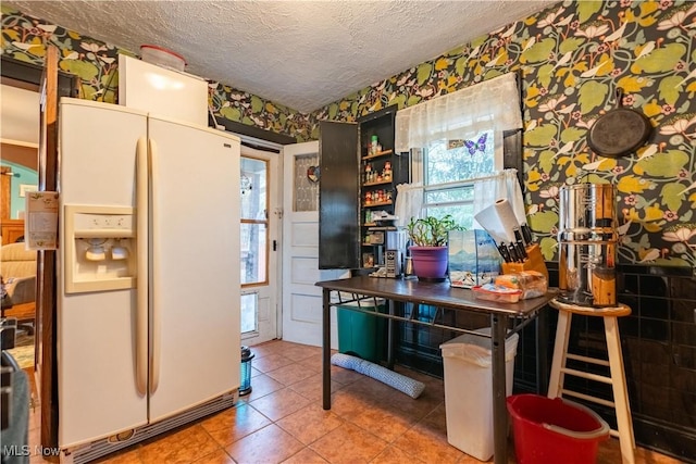 kitchen with a textured ceiling, white refrigerator with ice dispenser, and tile patterned flooring