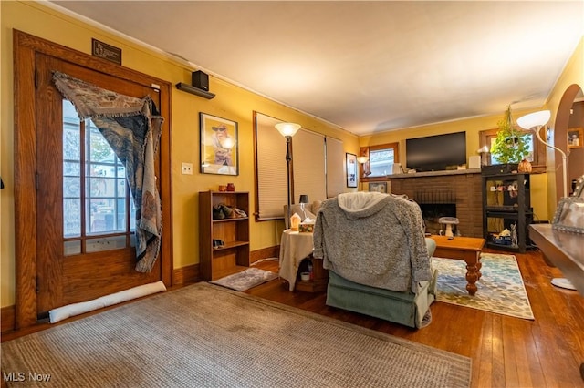 living room with hardwood / wood-style flooring, crown molding, and a fireplace