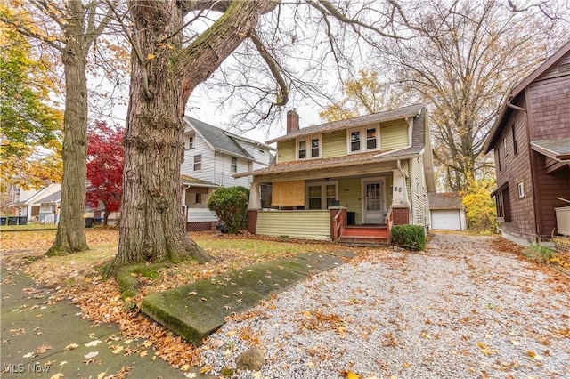 view of front facade featuring a porch, a garage, a front lawn, and an outdoor structure