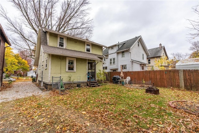 rear view of house featuring an outdoor fire pit and a yard