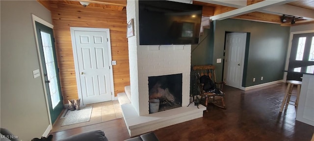 living area featuring wood walls, a brick fireplace, wood finished floors, and baseboards