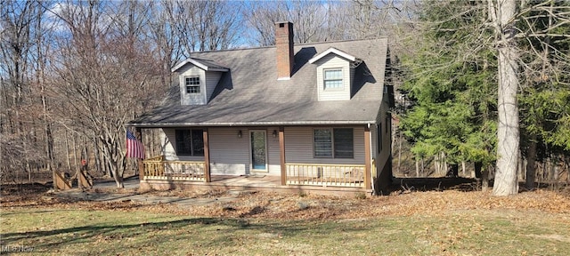 new england style home featuring a chimney, a front lawn, and a porch