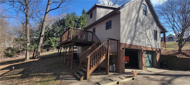 view of side of home featuring a deck, a garage, brick siding, driveway, and stairway