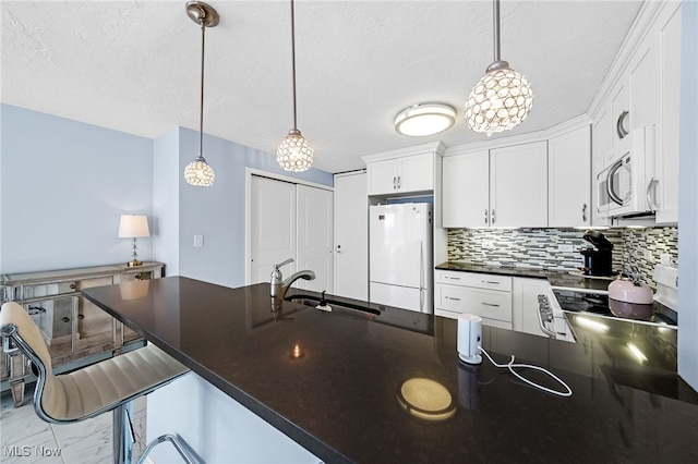 kitchen featuring decorative light fixtures, white appliances, white cabinets, and a breakfast bar area