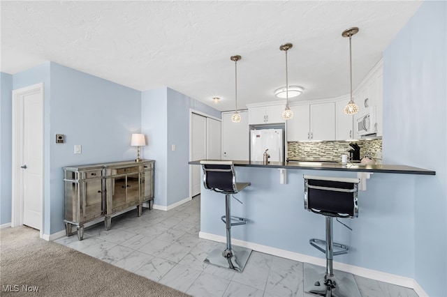 kitchen with a kitchen breakfast bar, kitchen peninsula, hanging light fixtures, white cabinetry, and white appliances