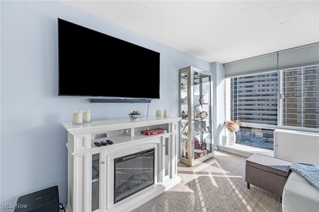 living room featuring carpet floors, plenty of natural light, a wall of windows, and a high end fireplace