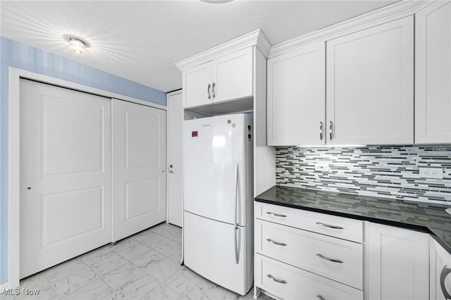 kitchen with white cabinets, backsplash, and white refrigerator