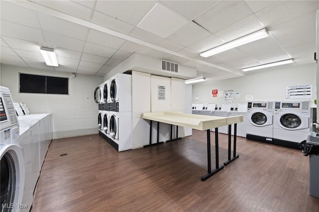 washroom featuring independent washer and dryer, stacked washing maching and dryer, and dark hardwood / wood-style flooring