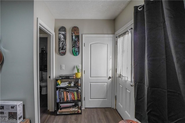 hallway with hardwood / wood-style floors and a textured ceiling