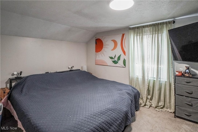 bedroom with light carpet, vaulted ceiling, and a textured ceiling