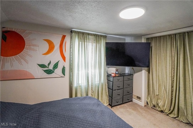 bedroom with light colored carpet and a textured ceiling