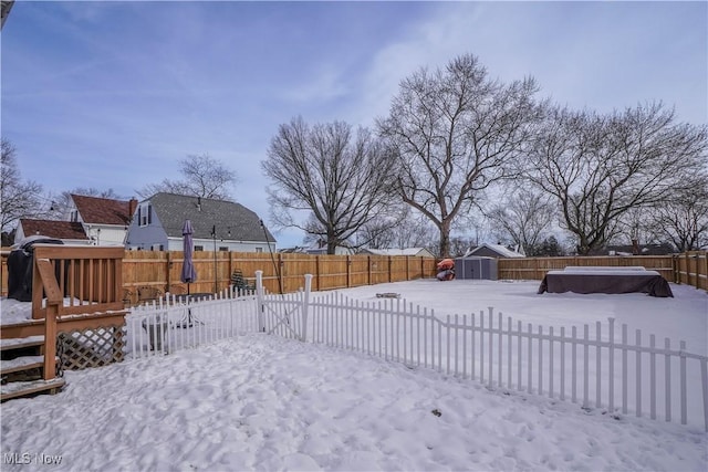 snowy yard featuring a storage unit and a hot tub